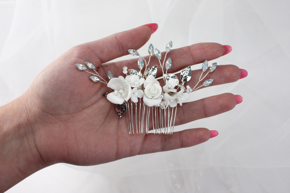 a woman's hand holding a white flower and crystal hair comb
