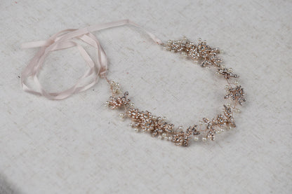 a bracelet with pearls and a ribbon on a table