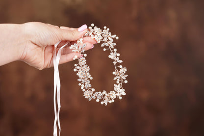 a woman holding a white necklace with flowers on it