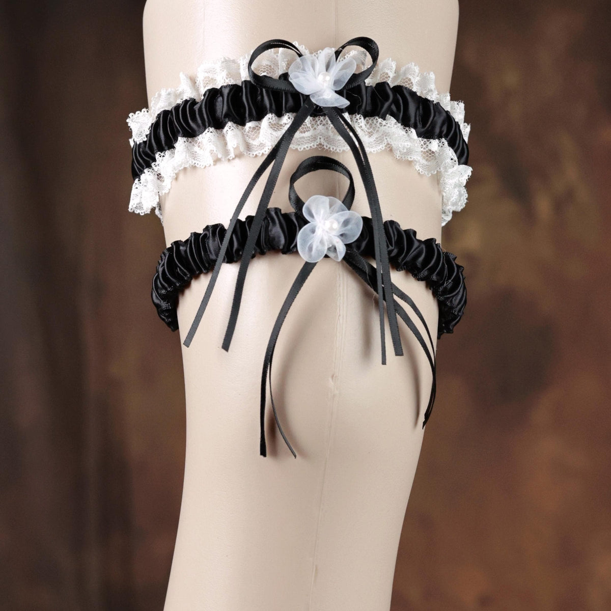 A mannequin wearing a black and white garter belt with white lace trim and black ribbons.