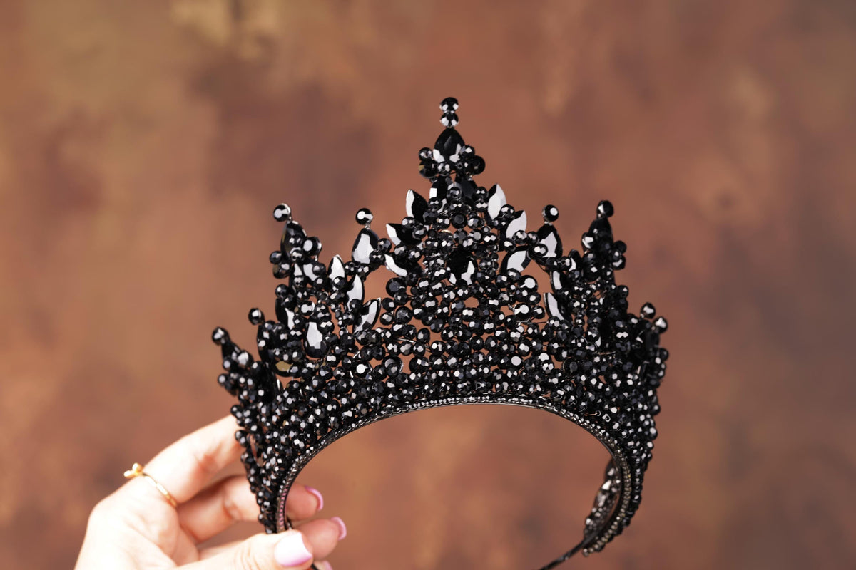 a hand holding a black tiara against a brown background