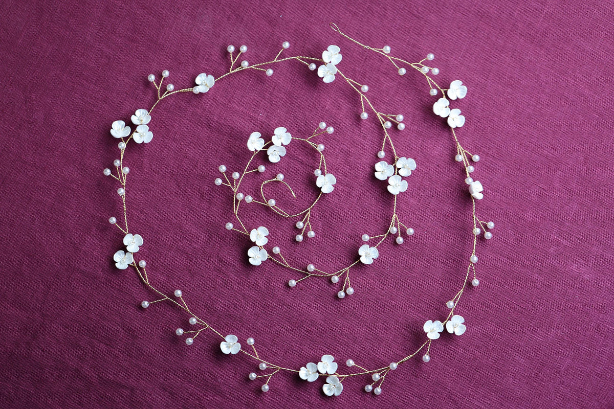 a necklace and bracelet with white flowers on a purple background