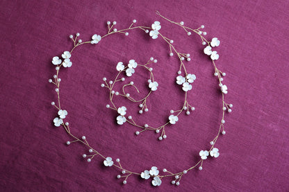 a necklace and bracelet with white flowers on a purple background