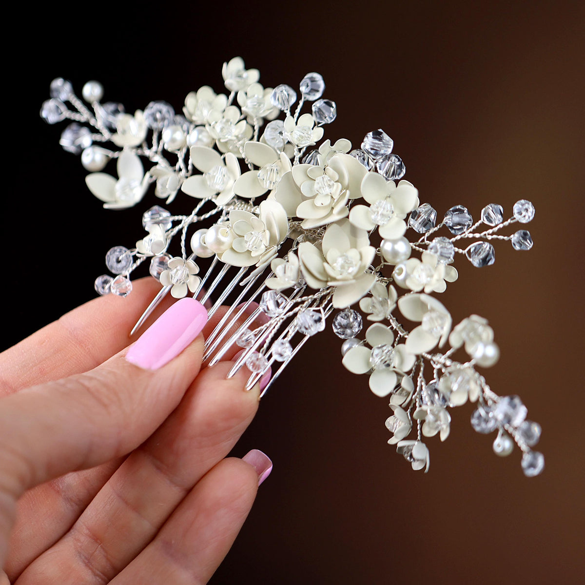 a hand holding a white flower and crystal hair comb