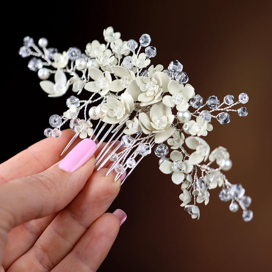 a hand holding a white flower and crystal hair comb