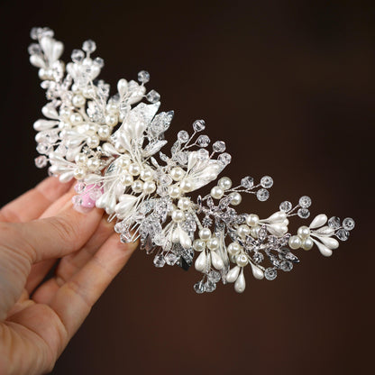 a hand holding a crystal and pearl hair comb