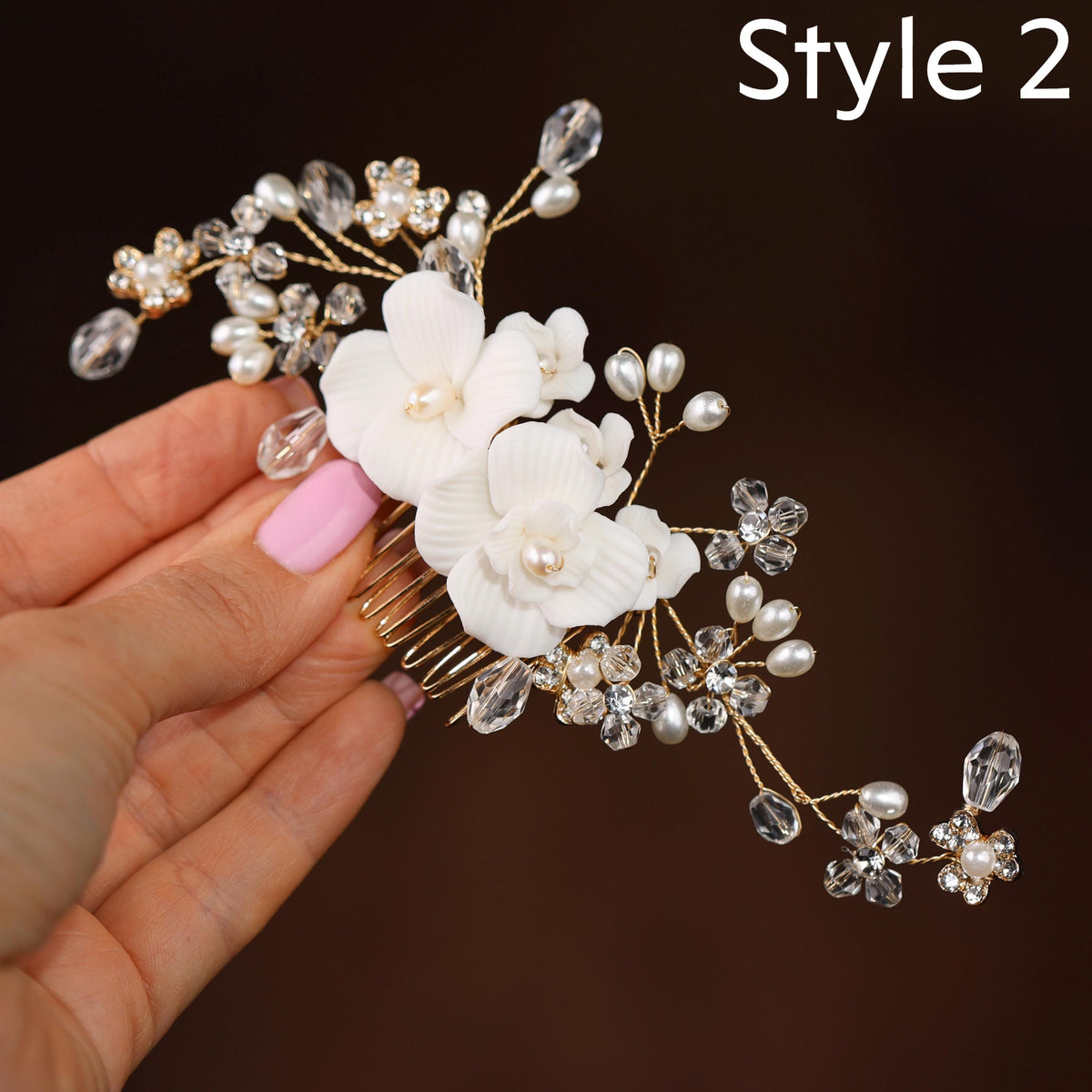 A hand holding a decorative hair accessory with white flowers and clear gemstones.