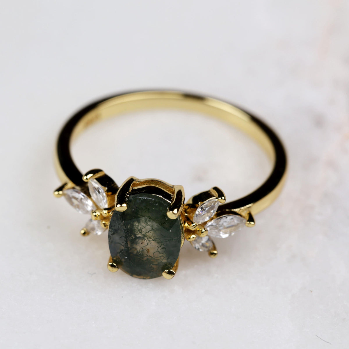 a gold ring with a green stone surrounded by diamonds