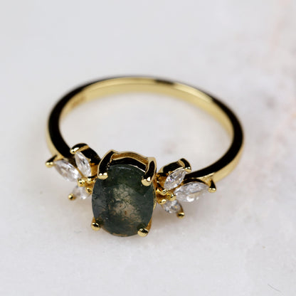 a gold ring with a green stone surrounded by diamonds