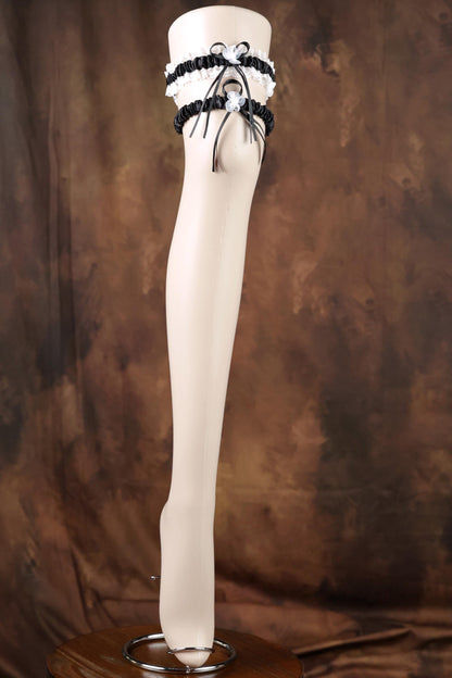A mannequin leg wearing a black and white garter belt and a black bow tie.
