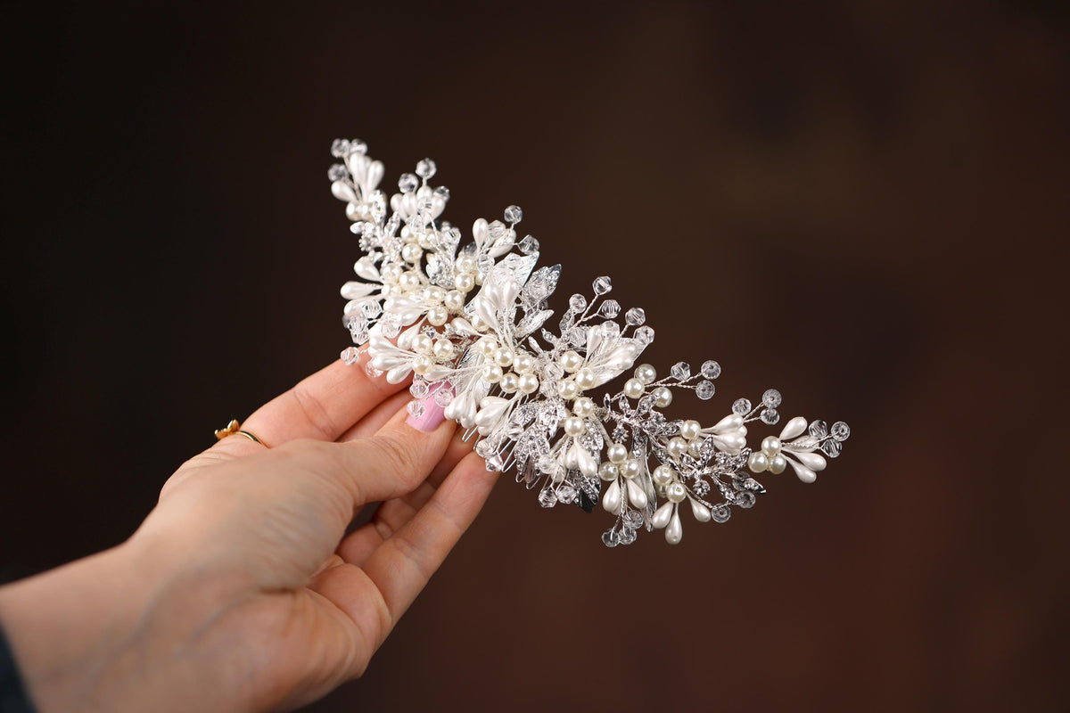a hand holding a white flower with pearls on it