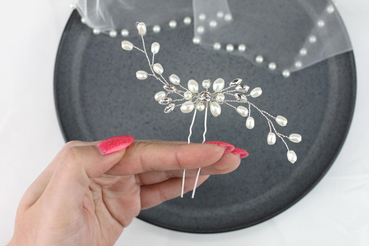 a person holding a piece of wire with pearls on it