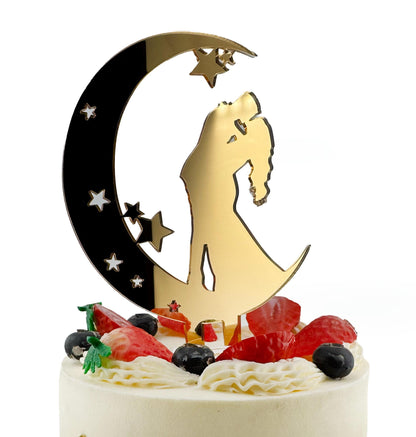 A white cake with a gold crescent moon and star-shaped decorations, including a silhouette of a couple embracing.