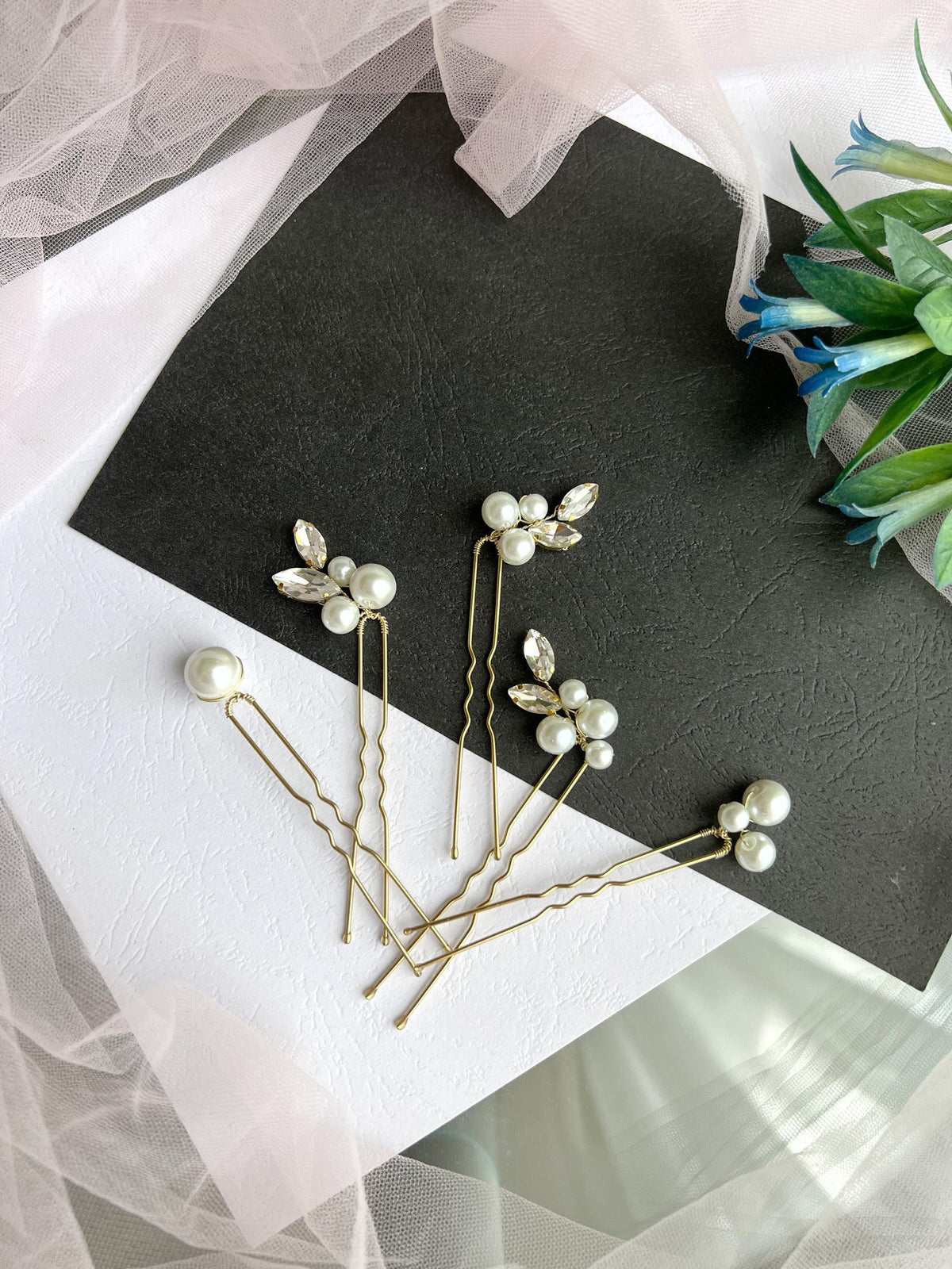 a pair of hair pins with pearls on top of a piece of paper