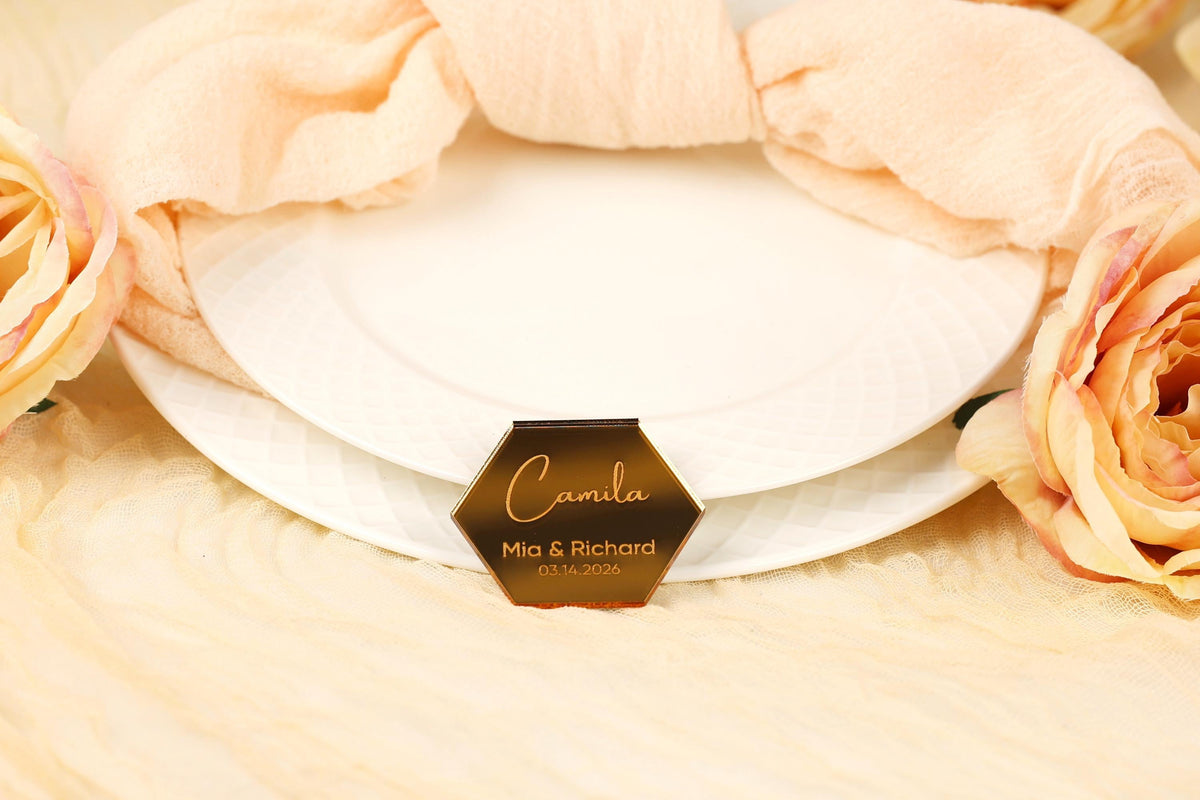 a white plate with a hexagonal label in the center, surrounded by a floral arrangement and a peach-colored fabric.