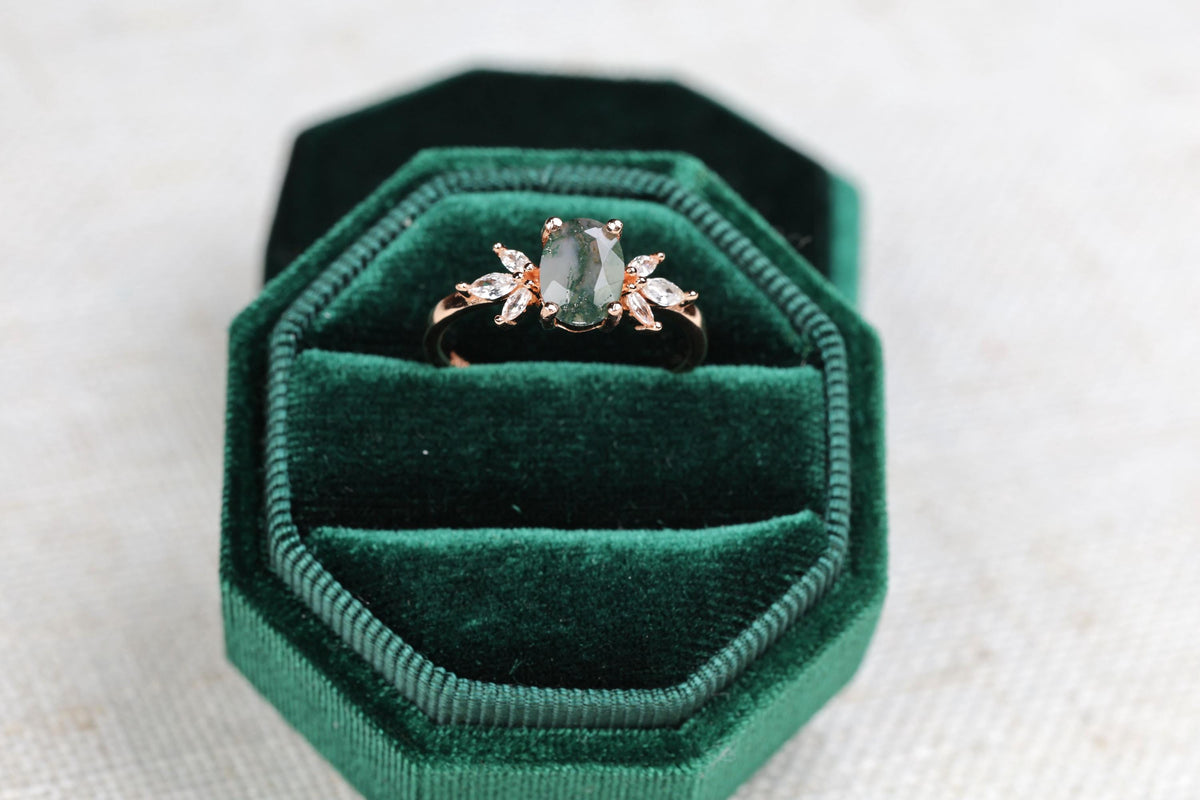 a green velvet ring box with a ring in it