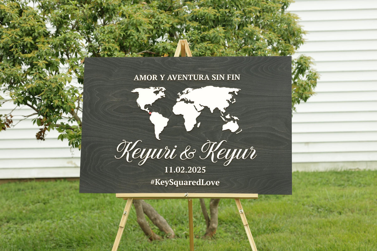 A black and white sign with a world map and text, standing on a wooden easel in front of a tree.