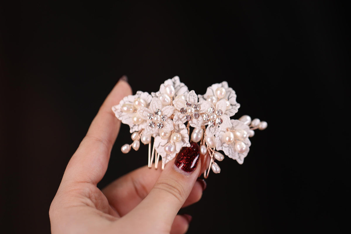 a hand holding a hair comb with pearls and pearls on it