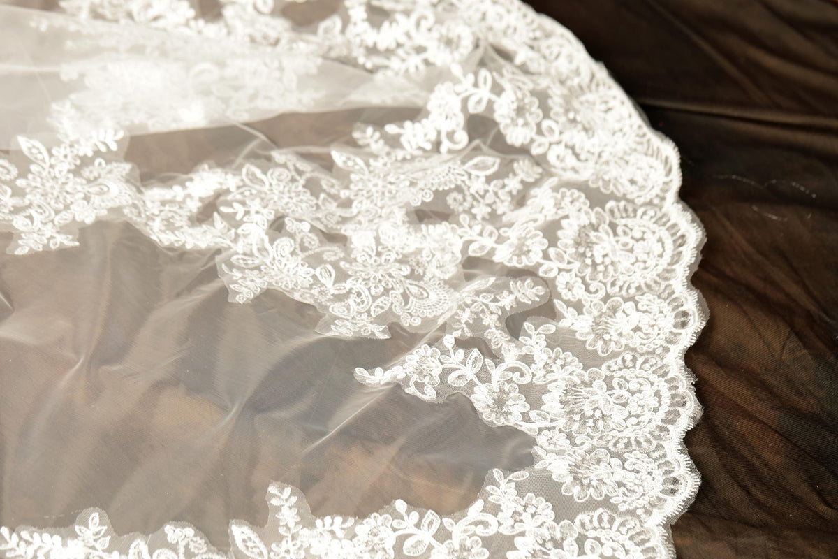 A close-up view of a delicate, white lace veil with intricate floral patterns.