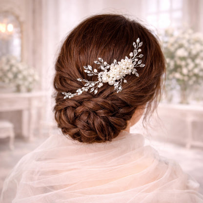 a woman's back view with her hair styled in a bun, adorned with a decorative hair accessory featuring white flowers and leaves.