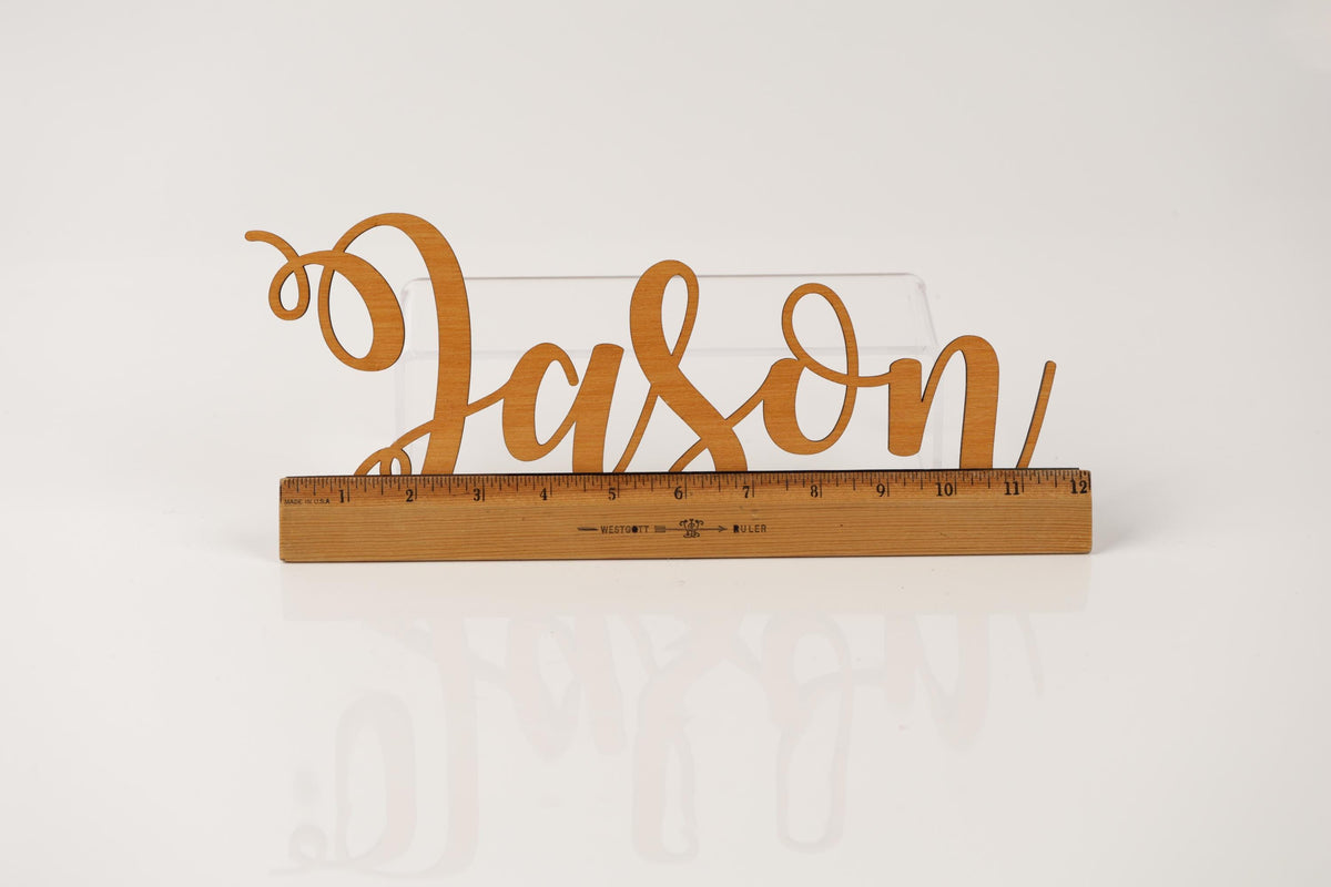 A wooden ruler with the word "JASON" written on it, placed on a white surface.