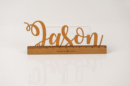 A wooden ruler with the word "JASON" written on it, placed on a white surface.