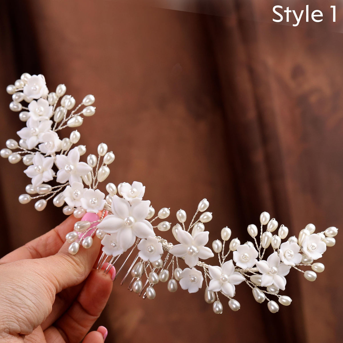 a hand holding a white flower and pearl hair comb
