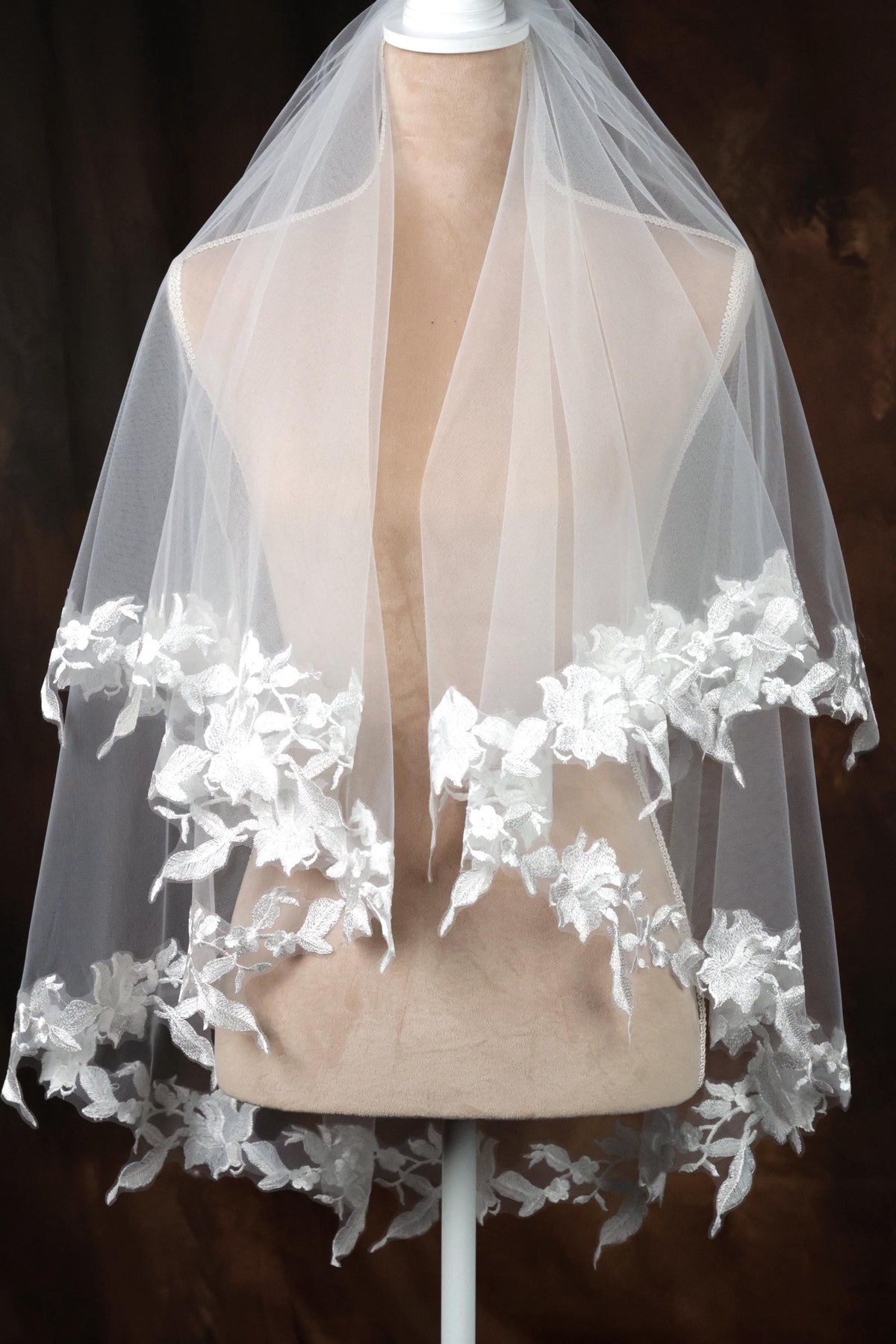 A mannequin wearing a white veil with delicate white lace flowers.