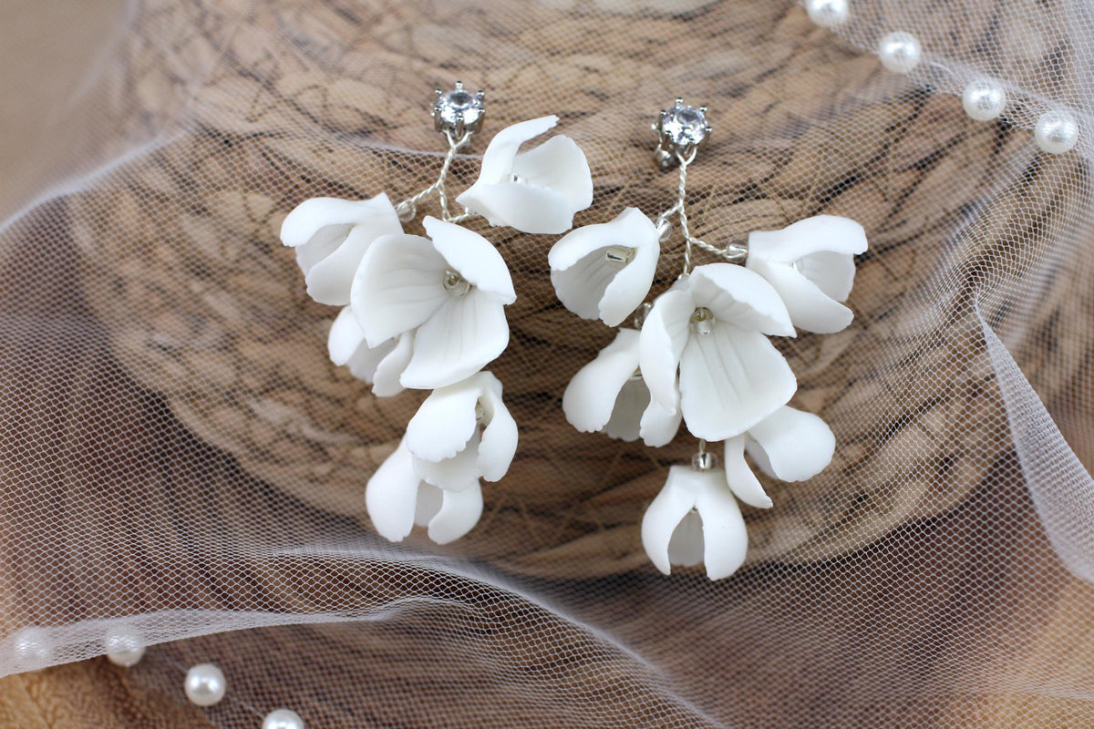 a close up of a pair of white flower earrings