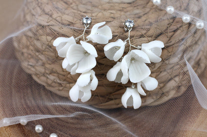 a close up of a pair of white flower earrings