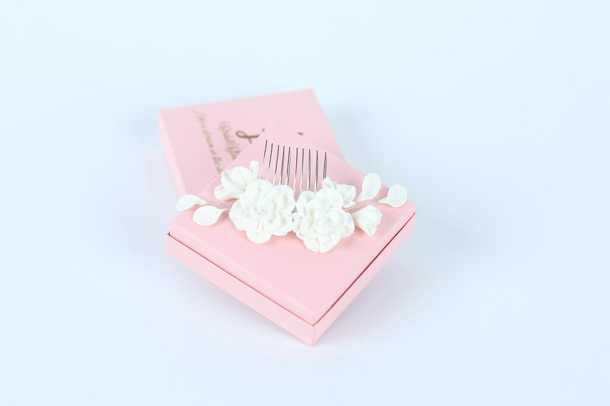 A pink box with a white comb and flowers on top, placed on a white background.