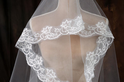 A close-up view of a delicate white wedding veil with intricate lace trim.