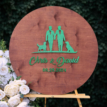 A wooden sign with a green silhouette of two people holding hands and a dog, along with the text "Chris & David" and the date "08.28.2024".