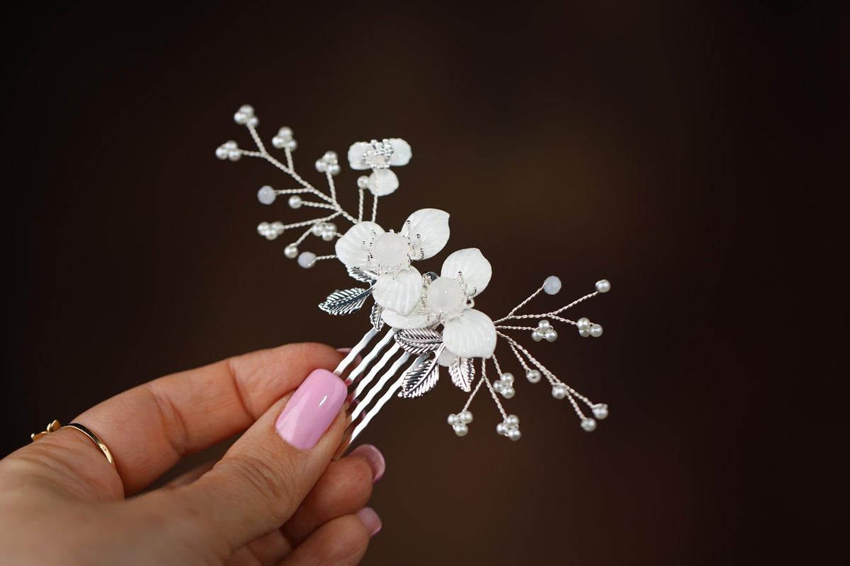 a hand holding a hair comb with flowers on it