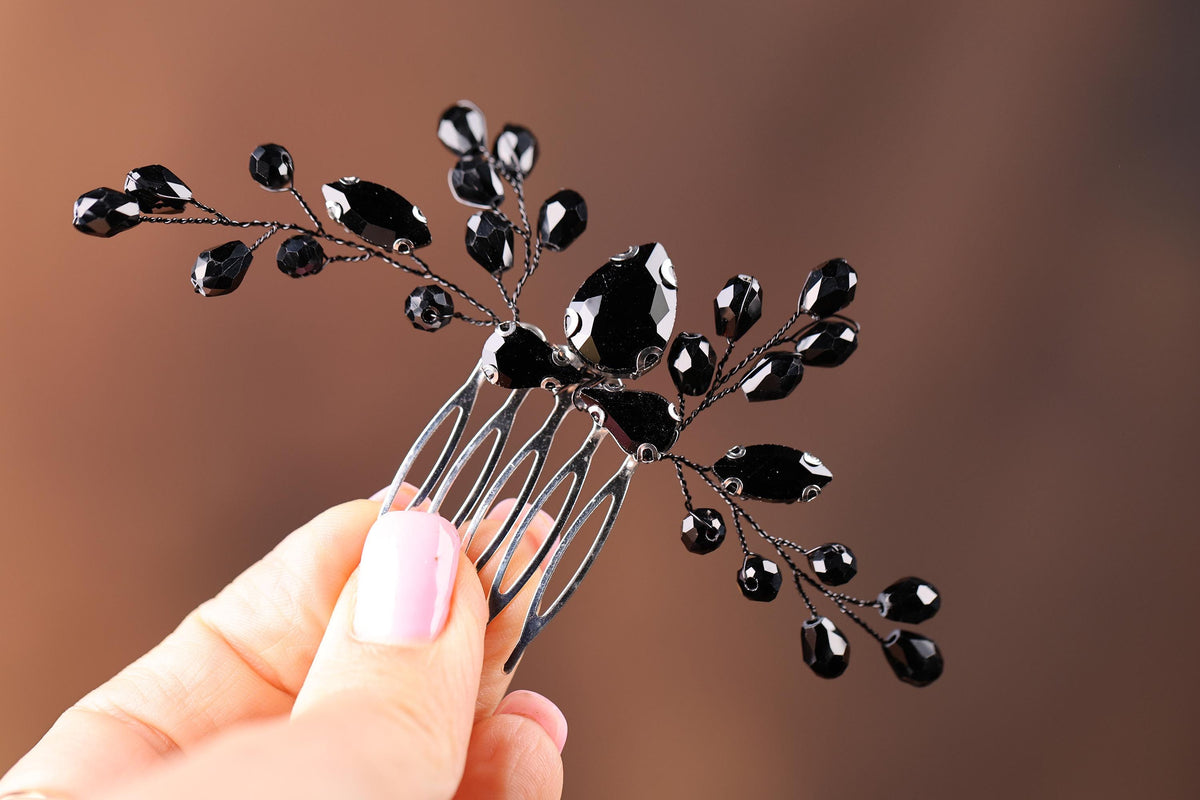 a hand holding a black and silver hair comb