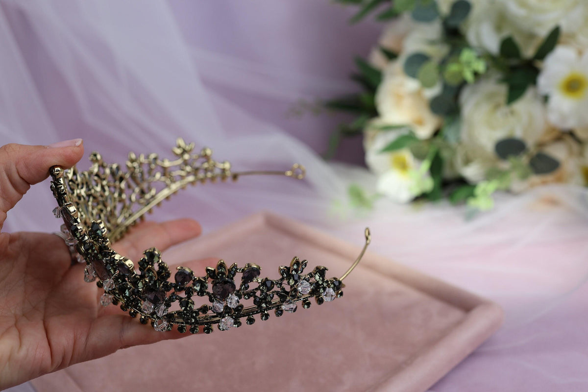 a hand holding a tiara next to a bouquet of flowers