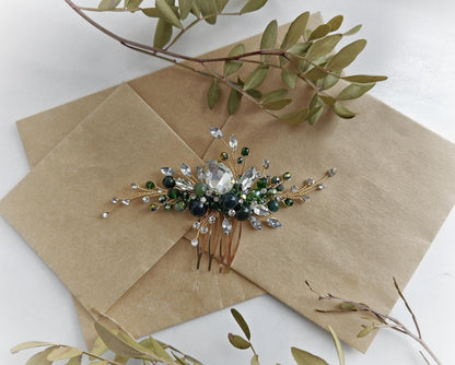 a decorative hair clip adorned with green and silver gemstones, placed on a brown paper surface.
