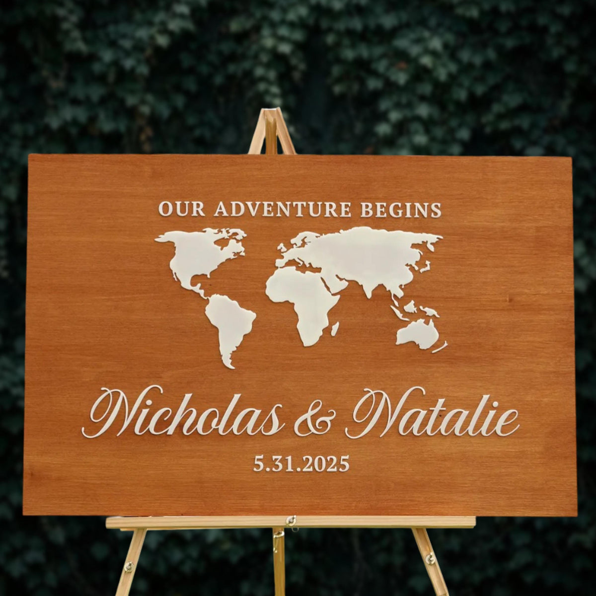 A wooden sign with a world map and the names "Nikolas & Natalie" printed on it, indicating that their adventure begins.
