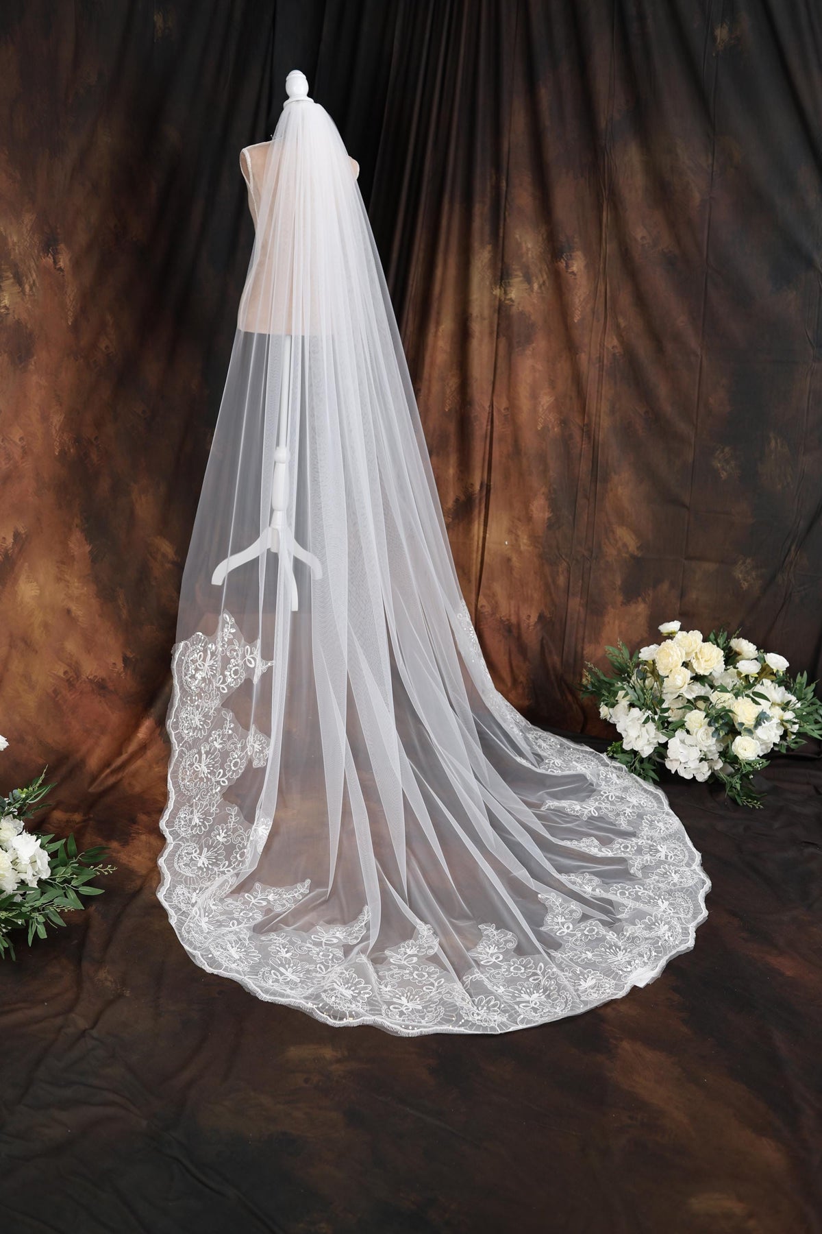a wedding veil on a mannequin next to a bouquet of flowers