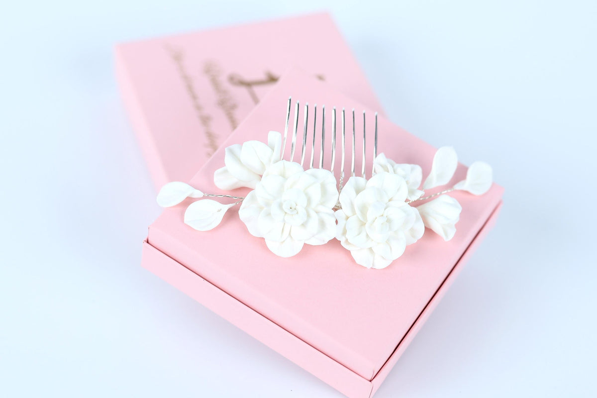 A pink box with a white flower-shaped hair accessory on top, placed on a white surface.