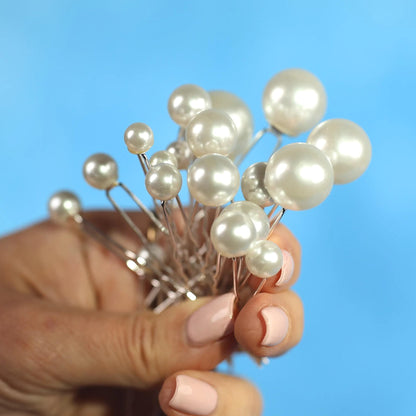 A hand holding a cluster of small, white pearls against a blue background.