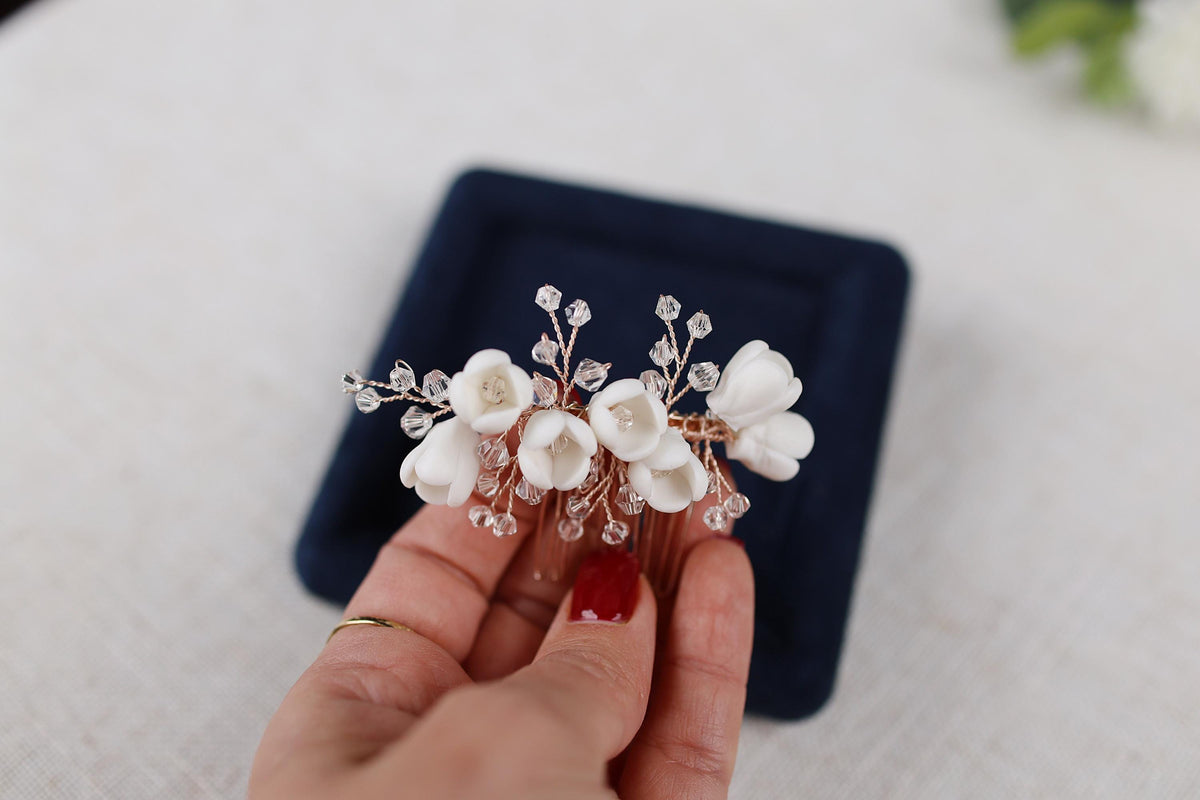 a woman is holding a white flower hair comb