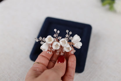 a woman is holding a white flower hair comb