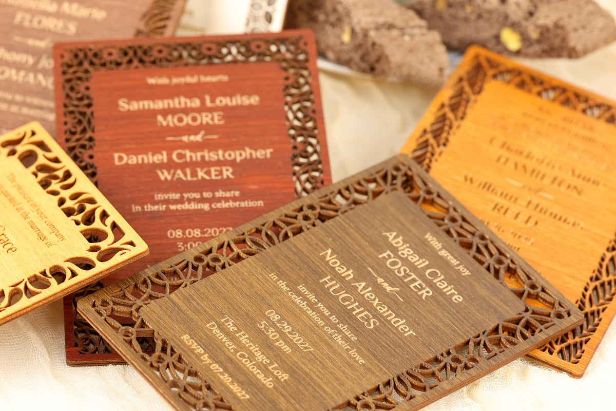 several wooden wedding invitations with intricate designs, arranged on a surface.
