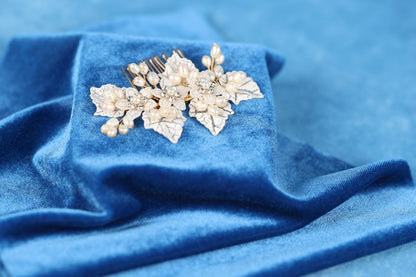 A close-up view of a decorative hair accessory, possibly a hair clip or headband, resting on a blue fabric surface.