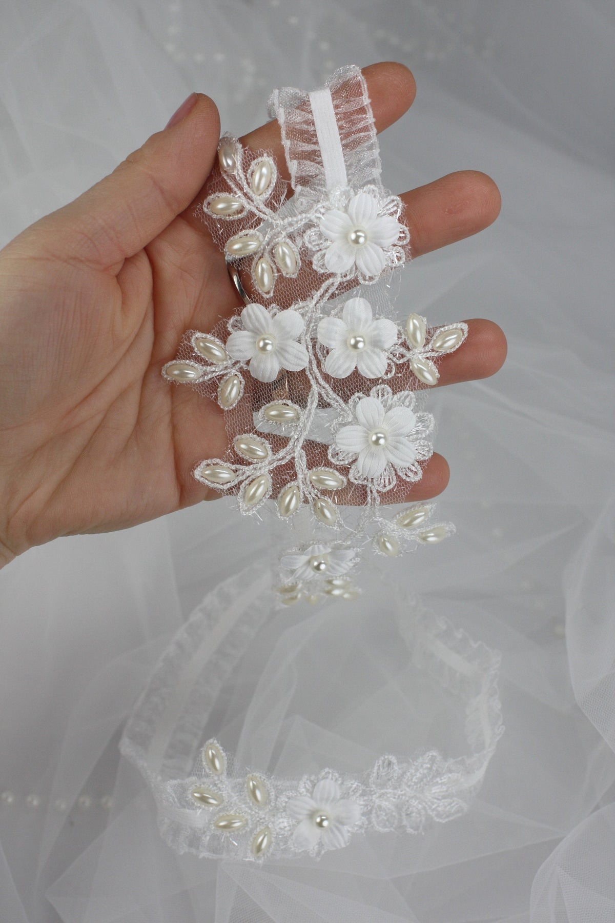 a hand holding a piece of wedding garter