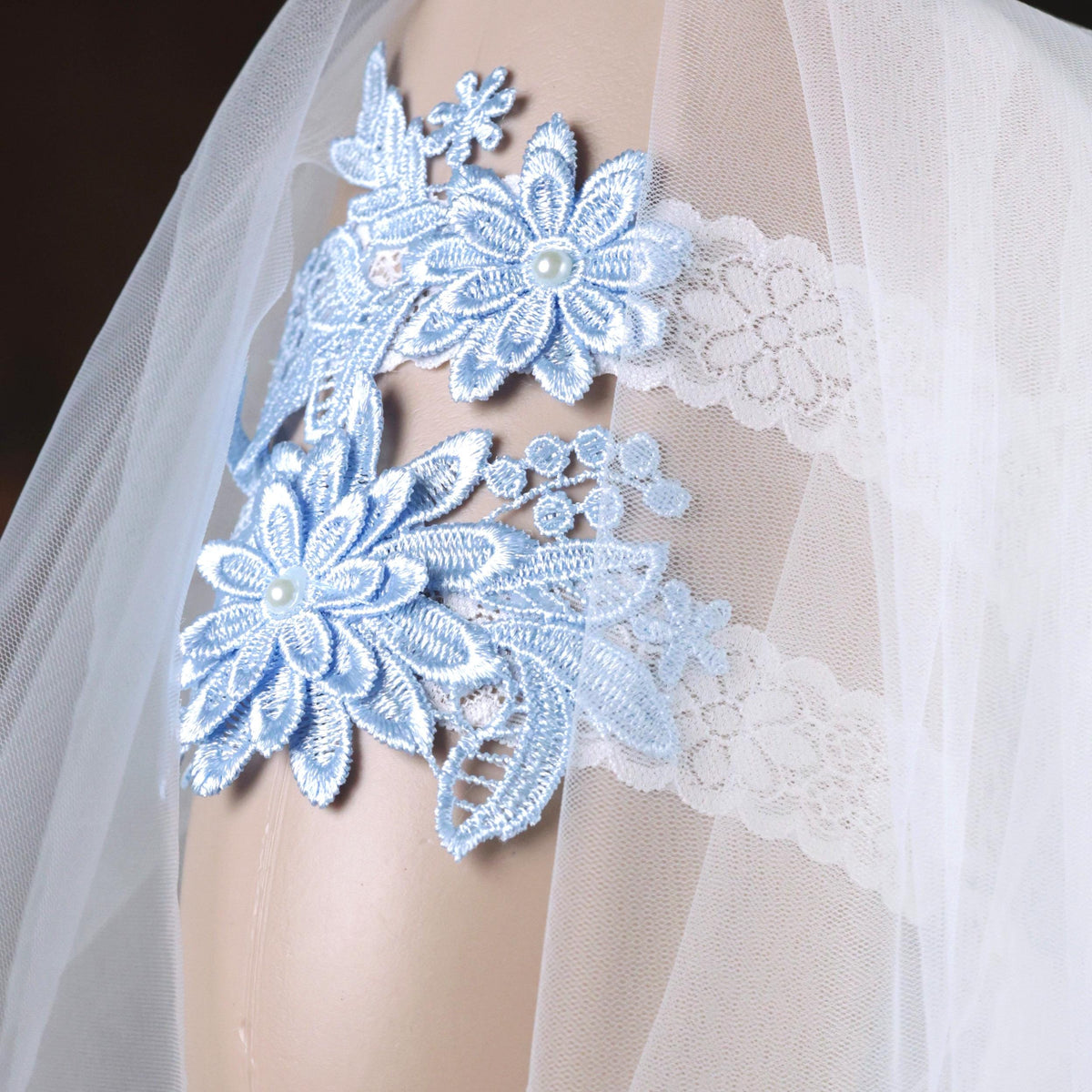 A close-up view of a delicate blue lace veil with intricate floral embroidery.