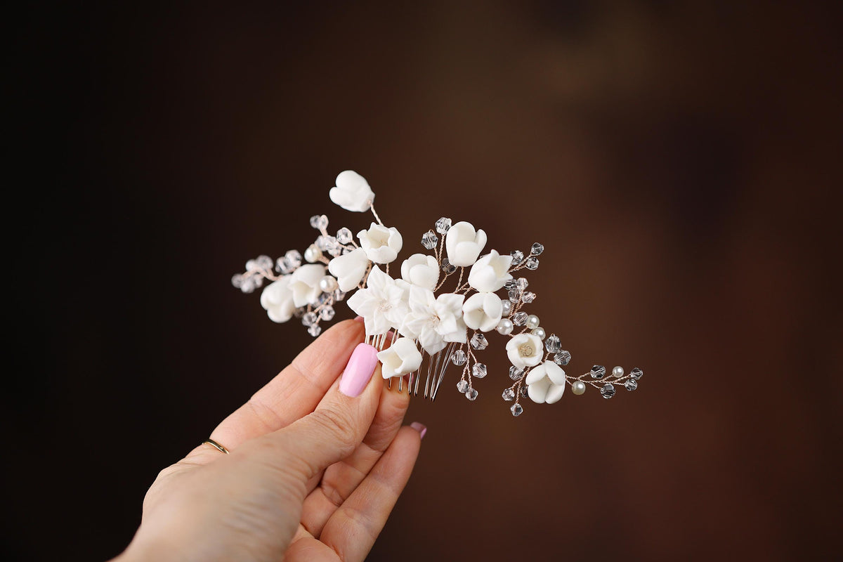 a hand holding a white flower and a hair comb