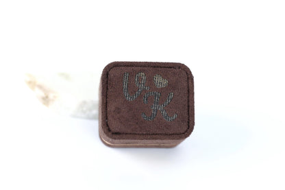 A brown, square-shaped object with the letters "VJ" printed on it, sitting on a white background.