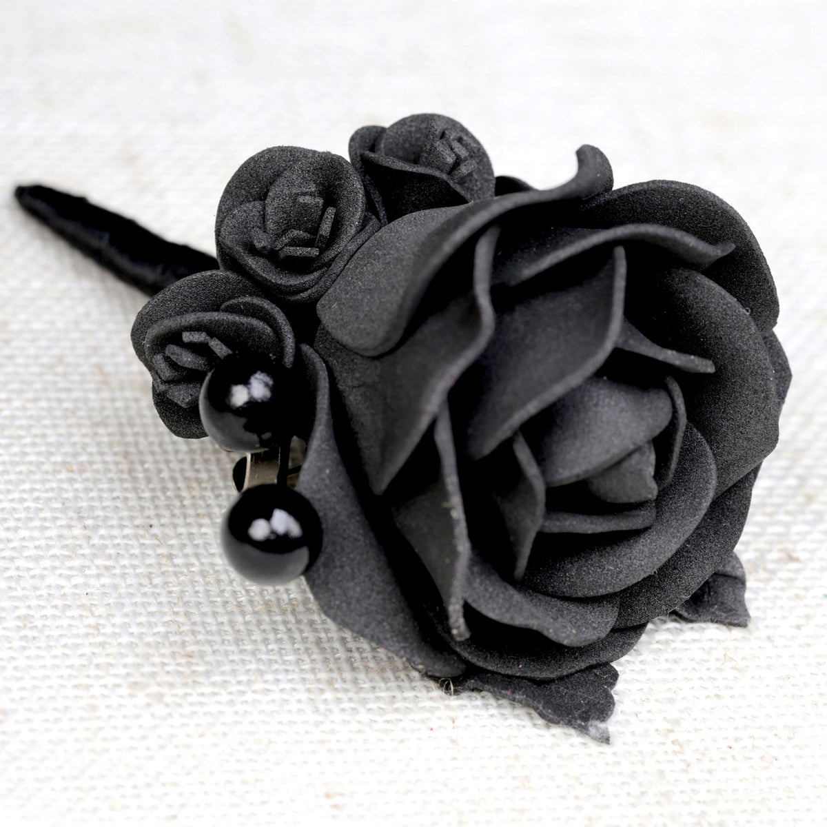 a close up of a black rose on a white surface